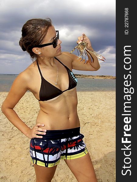 Young girl standing on the beach and holding a blue crab. Young girl standing on the beach and holding a blue crab