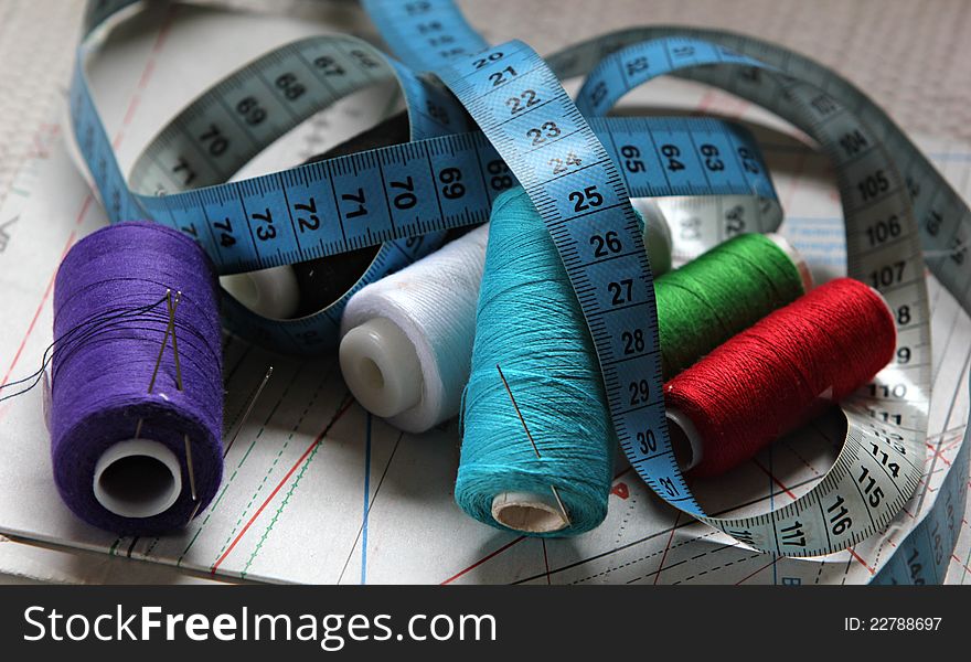 Threads, needles ,  and a measuring tape on sewing plan. Threads, needles ,  and a measuring tape on sewing plan