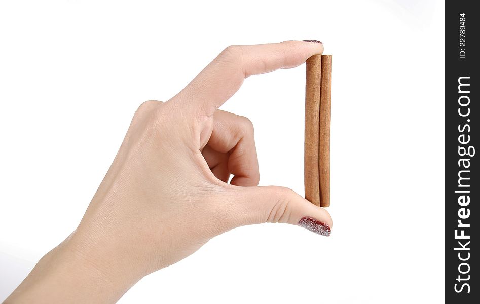 Female hand holding the cinnamon stick on a white background