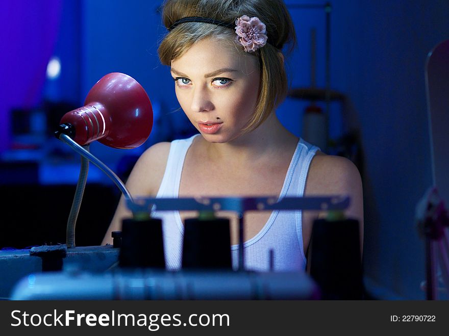 Seductive blond sewing in her workshop a red squared shirt