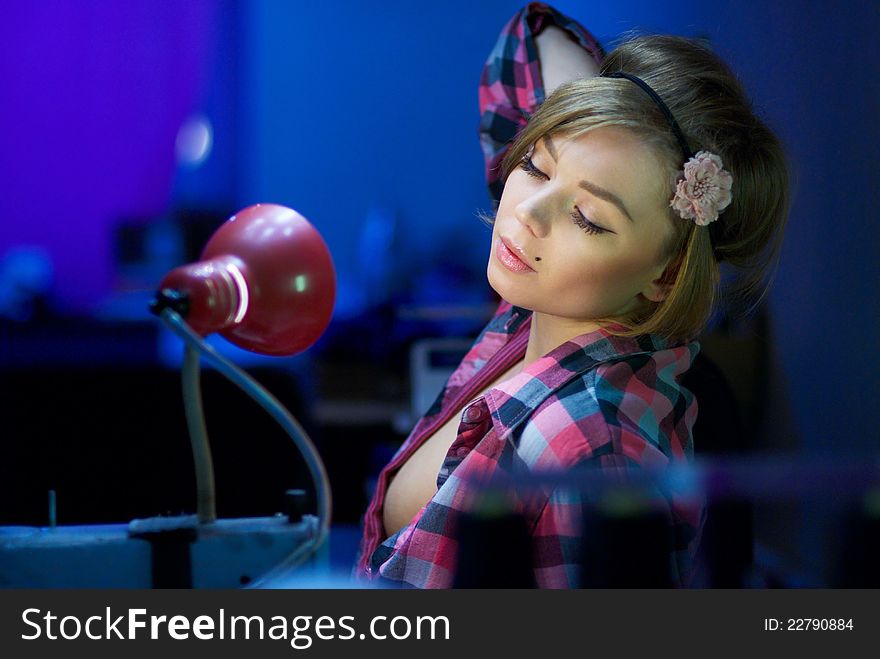 Seductive blond sewing in her workshop a red squared shirt