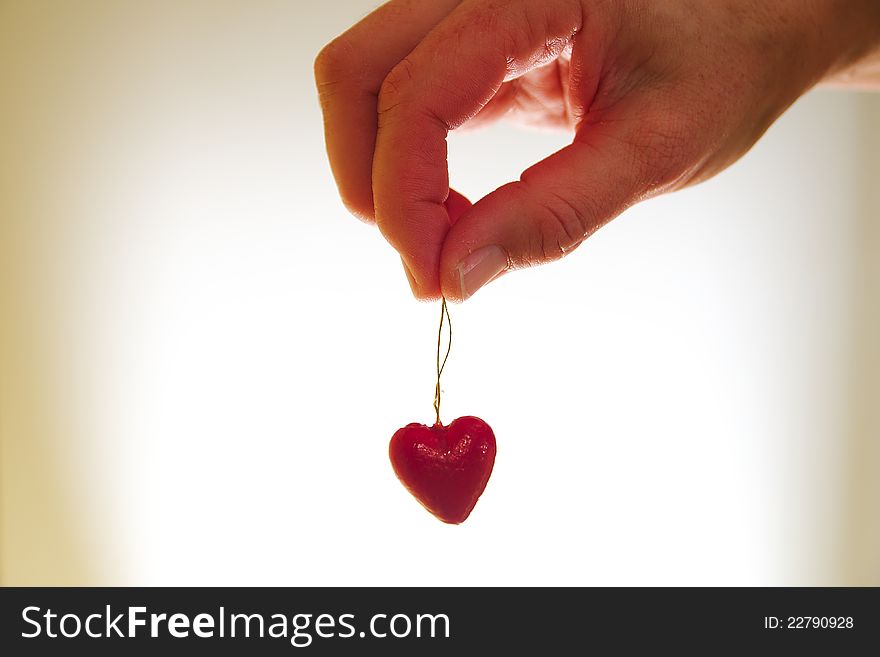 Woman hand holding red valentine heart on golden string. Woman hand holding red valentine heart on golden string