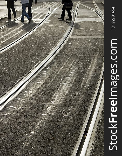 Pedistrians cross silvery grey tramlines in Munich, Germany. Pedistrians cross silvery grey tramlines in Munich, Germany