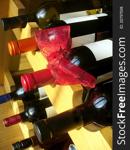 Wine Bottles With Red Ribbon Stacked On Wooden Rac