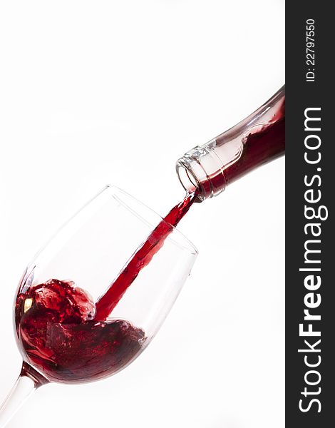 Red wine pouring into glass, isolated on white background