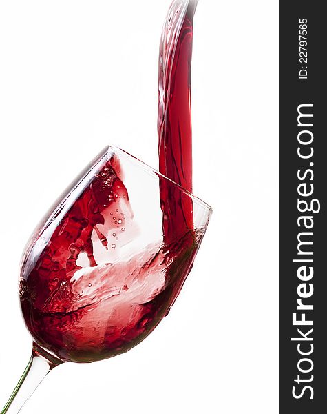 Red wine pouring into glass, isolated on white background