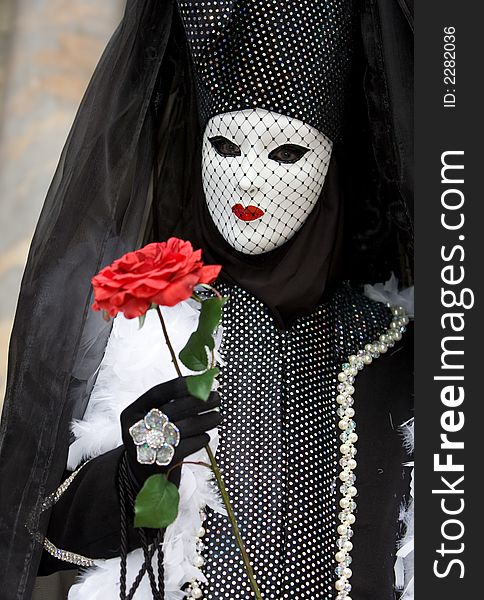 A venetian lady with a white mask, red lips and a red rose. A venetian lady with a white mask, red lips and a red rose