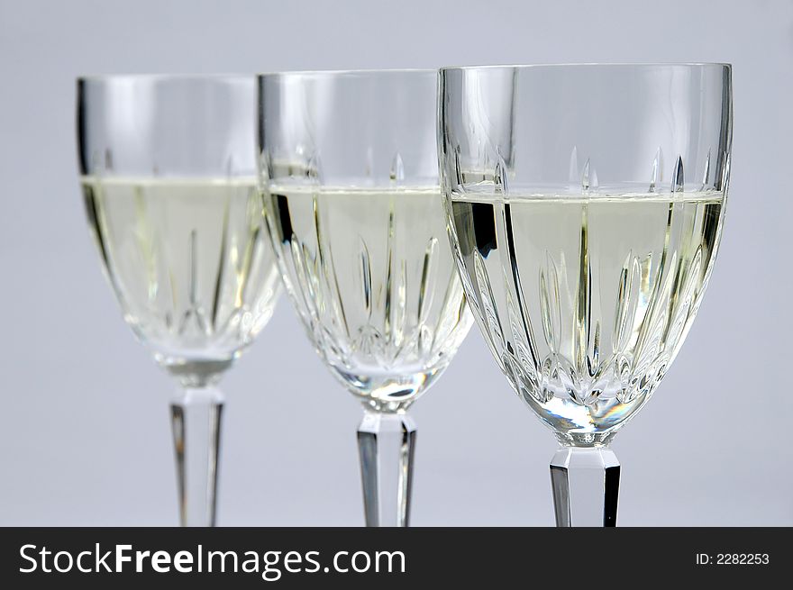 Three Glasses of white wine with selective focus over a neutral background. Three Glasses of white wine with selective focus over a neutral background.
