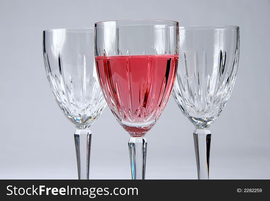 Three crystal glasses with selective focus. One with Zinfandel wine. Composition over a neutral background. Three crystal glasses with selective focus. One with Zinfandel wine. Composition over a neutral background.