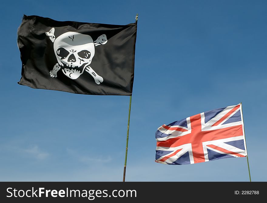 Skull and crossbones and GB union flag against blue sky. Skull and crossbones and GB union flag against blue sky