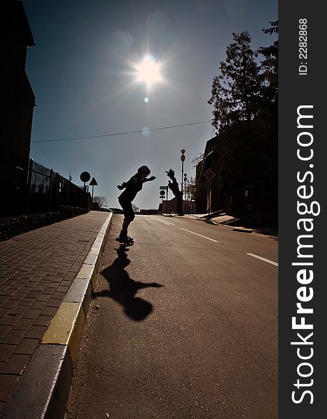 Silhouette of practicing skater on rollers in city area. Silhouette of practicing skater on rollers in city area