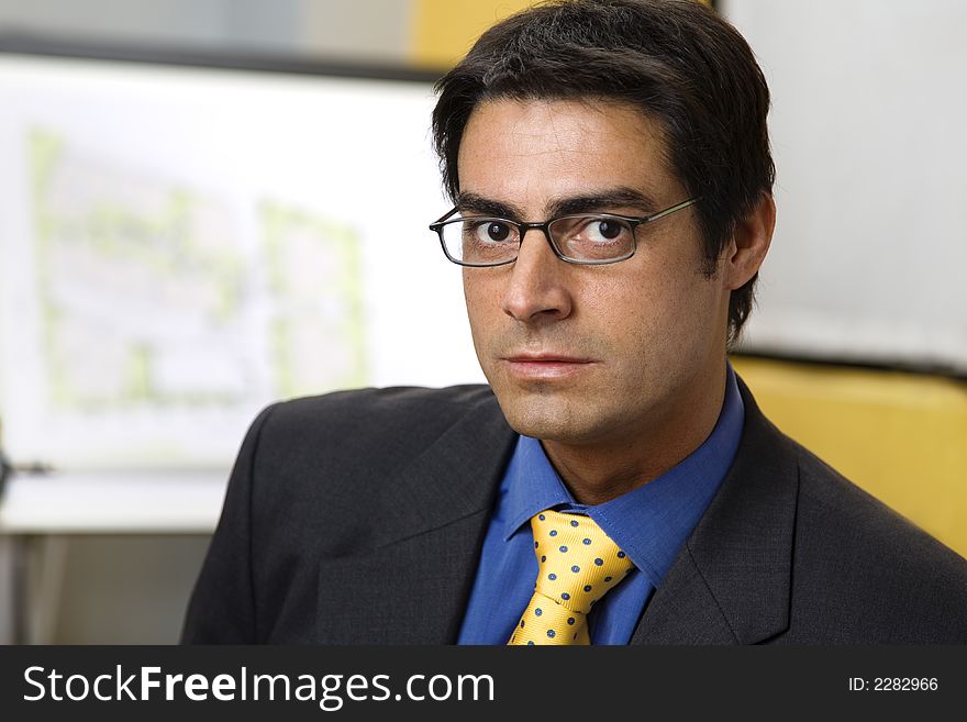 Work place: successful businessman smiling and staring at the camera