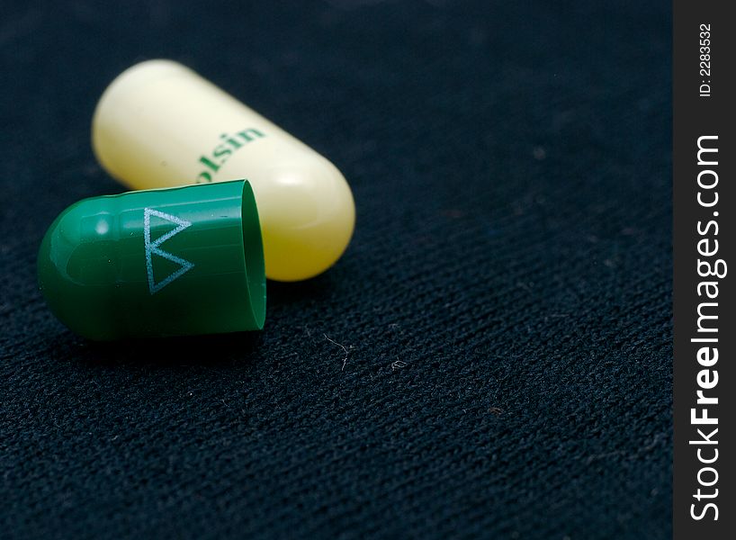 Green and white pill on a black background. Green and white pill on a black background