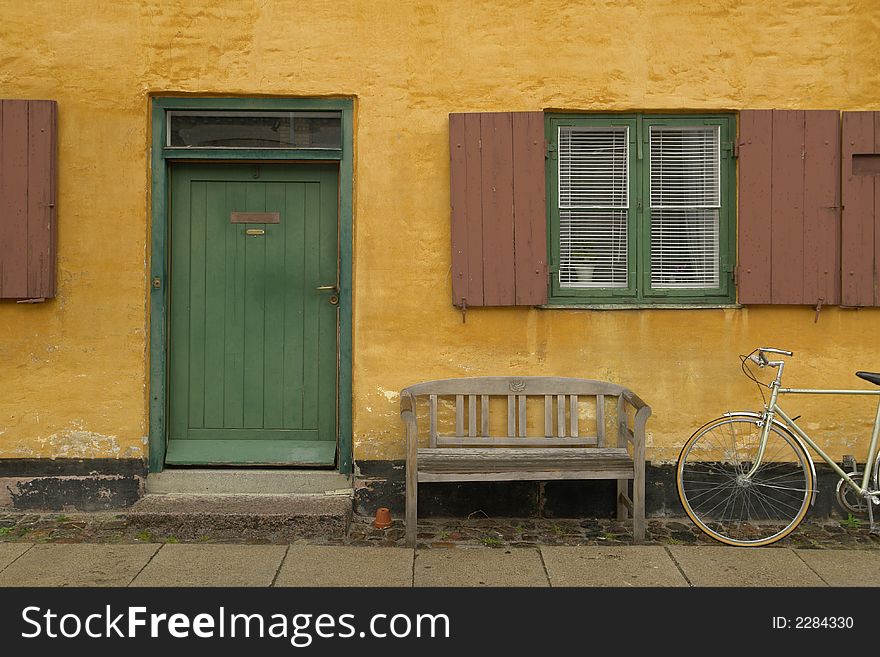 Entrance of old yellow house with green door and bicykle