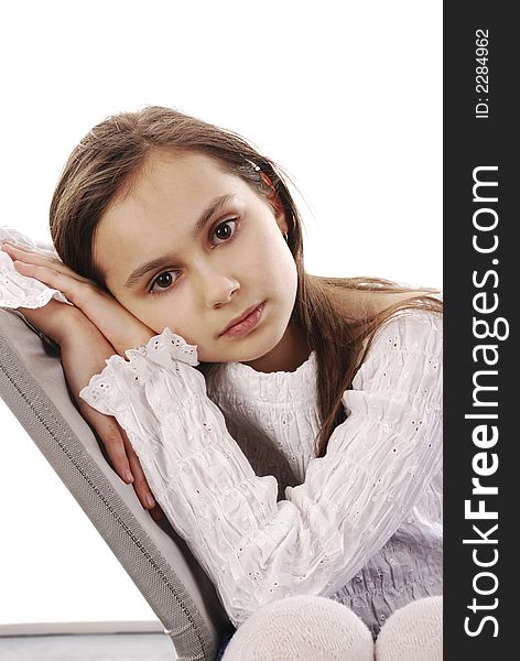 Young girl sitting on chair looking towards camera. Studio shot on white background. Young girl sitting on chair looking towards camera. Studio shot on white background.