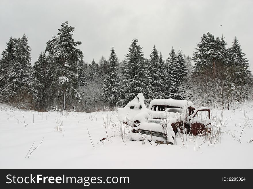 Old car in snow near forest at winter time