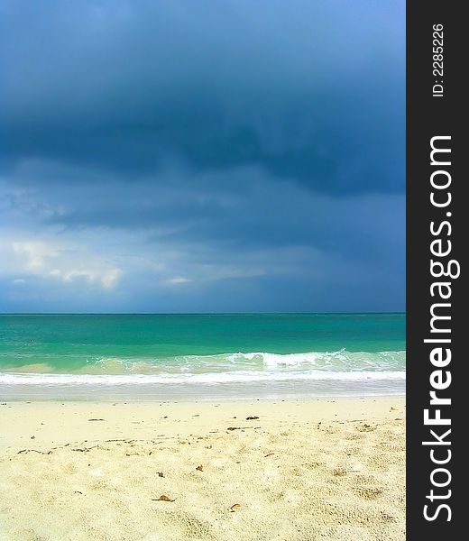 Dark clouds announcing approaching storm with white sand and turquoise waters