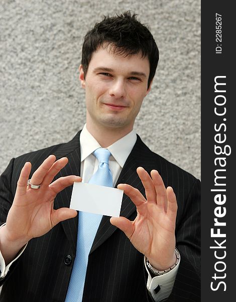 Businessman holds a blank card - add your own text. Focus on the card.