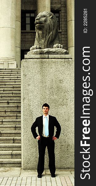 Businessman standing in front of a lion statue. Businessman standing in front of a lion statue