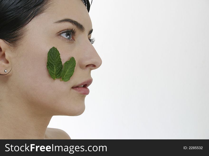 Beautiful woman with two leafs of green mint on hear cheek. Beautiful woman with two leafs of green mint on hear cheek.