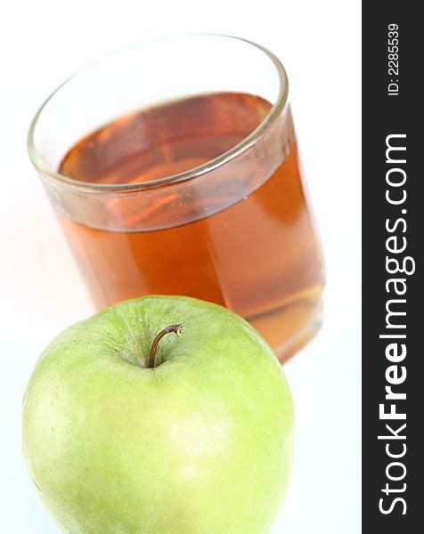 Green apple and glass of juice on a white background