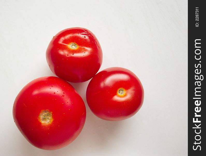 Three fresh red tomatoes over a light background. Three fresh red tomatoes over a light background