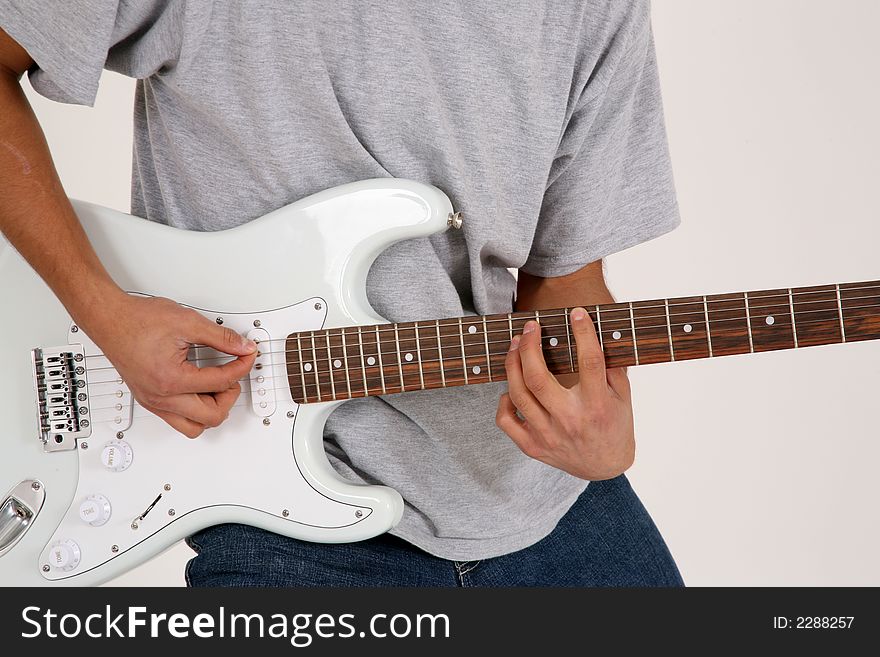Torso of a guy playng an electric guitar against a high key backgrund. Torso of a guy playng an electric guitar against a high key backgrund