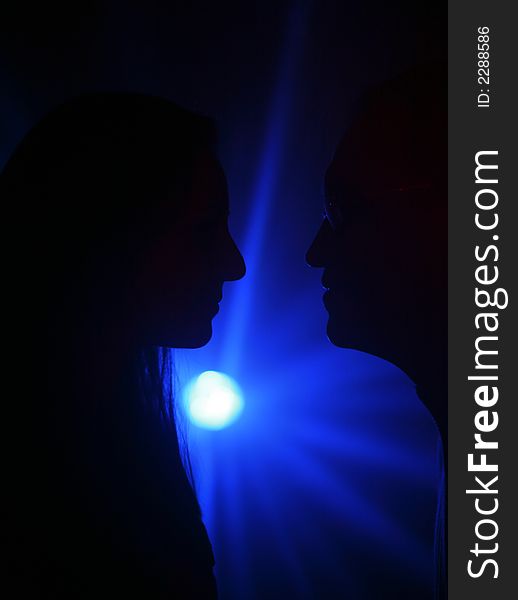 Two people in silhouete on a dark blue background. Two people in silhouete on a dark blue background