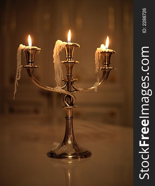 Three burning candles in an ancient gold candelabrum. Three burning candles in an ancient gold candelabrum