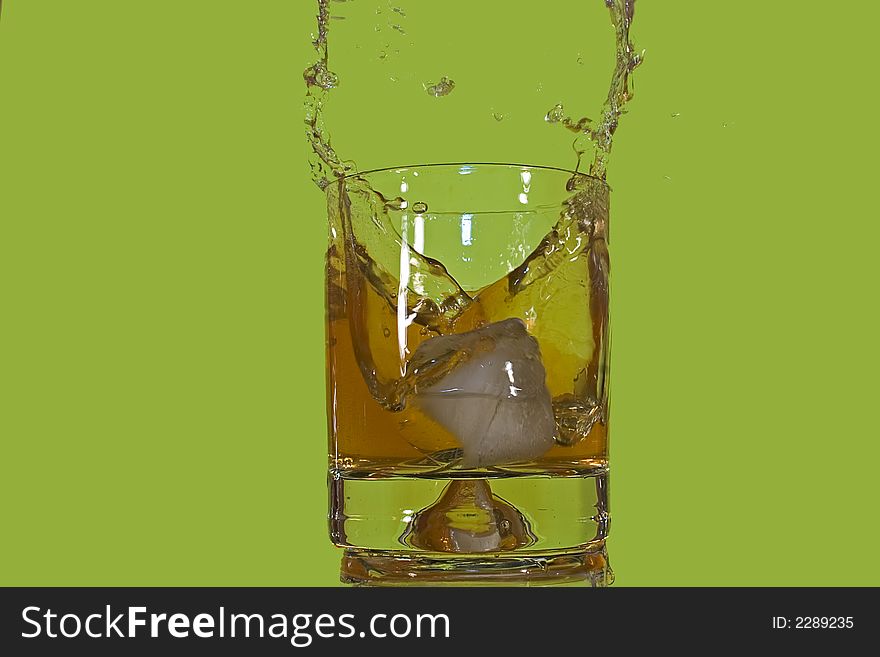 Ice floe falling into scotch glass causing from the splashes. Ice floe falling into scotch glass causing from the splashes