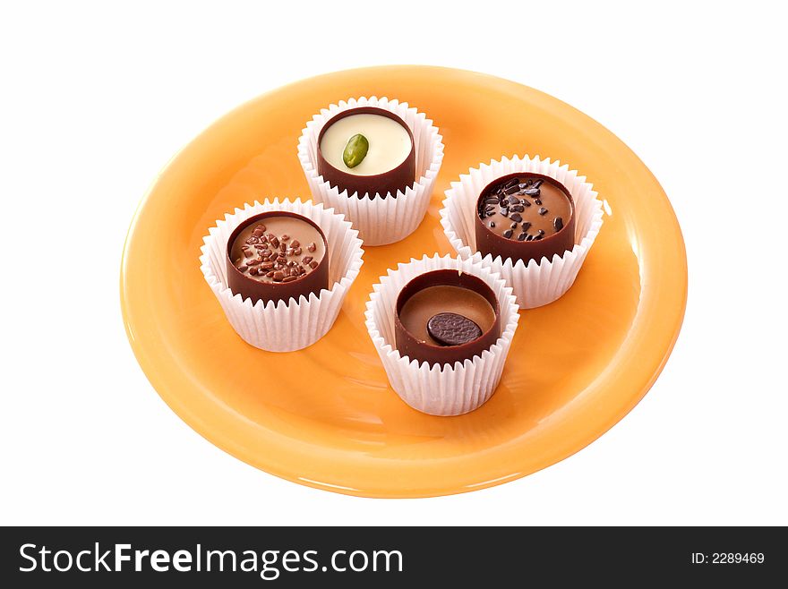 Four small candies on an orange plate. Four small candies on an orange plate