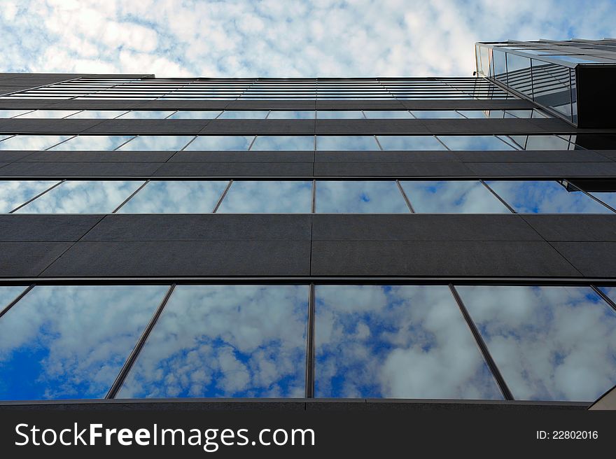 Portrait of modern office building with windows reflecting a cloudy sky. Portrait of modern office building with windows reflecting a cloudy sky