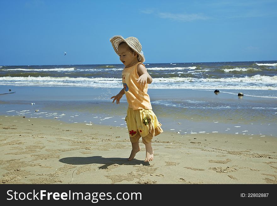 A child wearing a hat against the sea, jumping on the beach