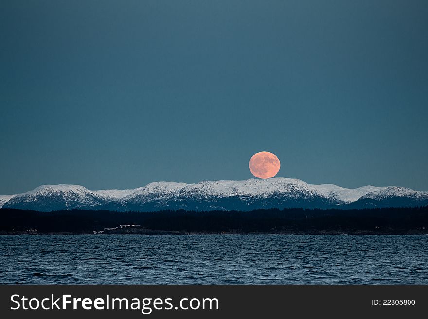 Rising red moon over the snowy Norwegian mountains. Rising red moon over the snowy Norwegian mountains