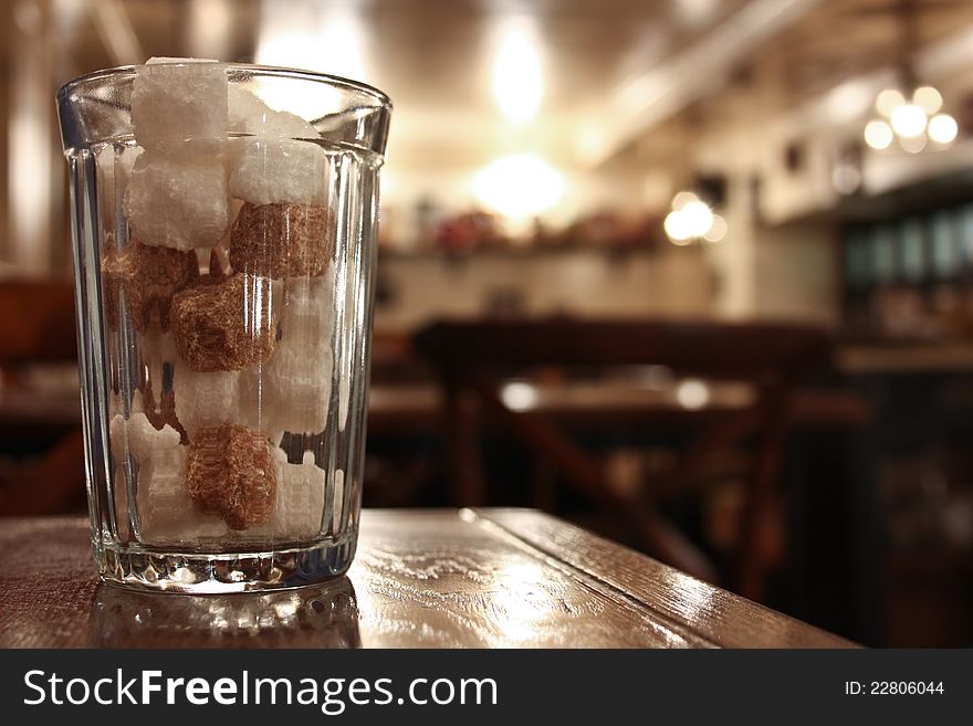 Cane and beet sugar in a glass beaker on a wooden table. Cane and beet sugar in a glass beaker on a wooden table