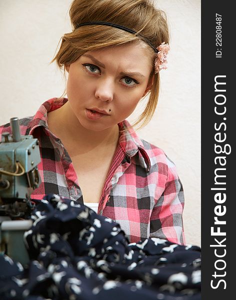 Woman seamstress posing near sewing machine in the workshop