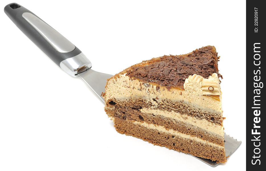 A piece of chocolate cake on a stainless steel spatula isolated on a white background. A piece of chocolate cake on a stainless steel spatula isolated on a white background