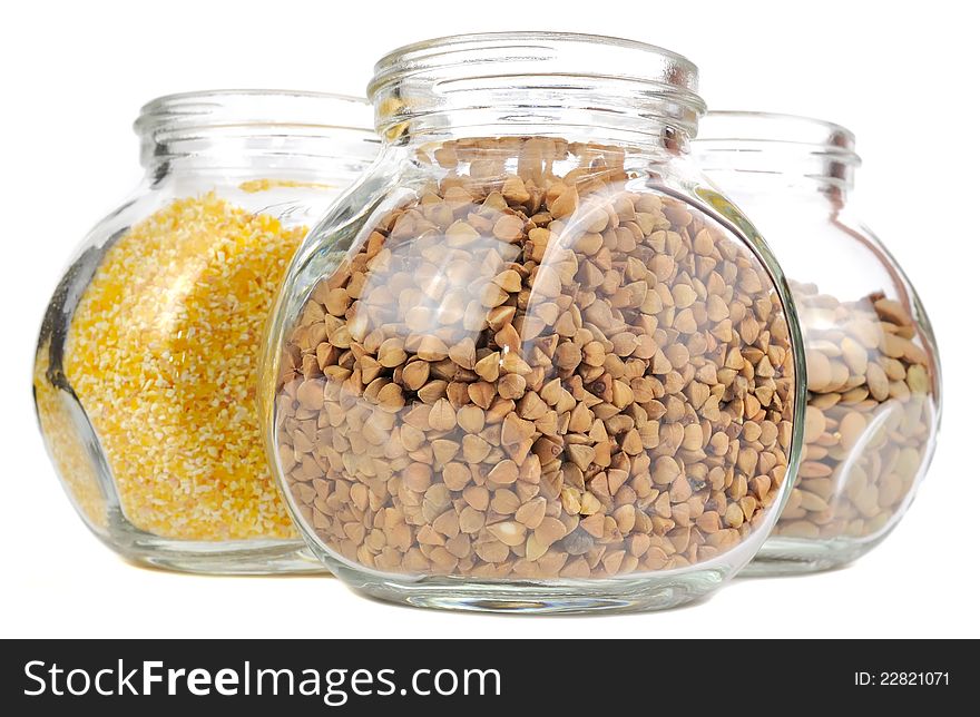 Glass jars with buckwheat, corn grits and lentils isolated on a white background