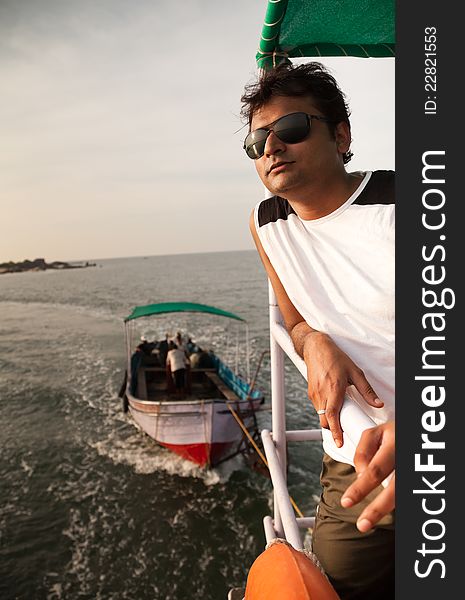 Indian Happy young man standing on boat in ocean  with sunglasses. Indian Happy young man standing on boat in ocean  with sunglasses