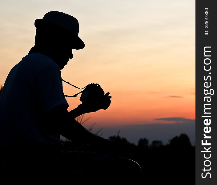 Photographer silhouette, staring at a camera review. Photographer silhouette, staring at a camera review.