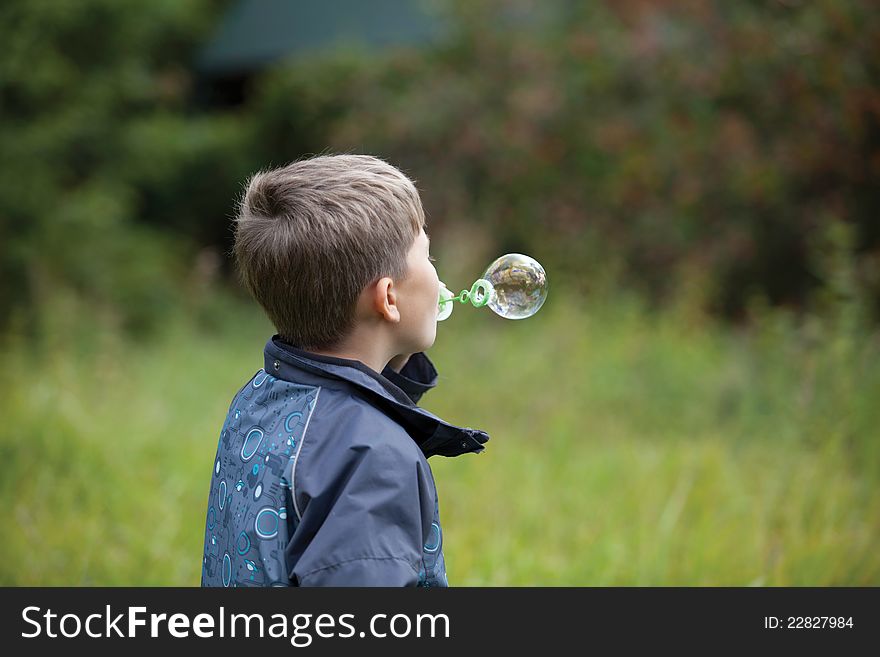 The boy starts up soap bubbles in countryside