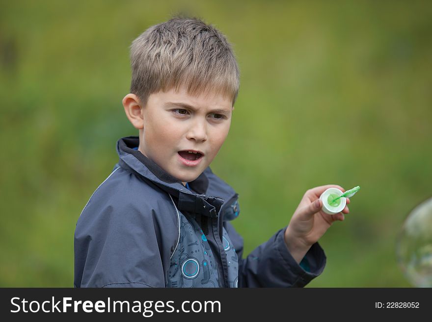 The boy starts up soap bubbles in countryside