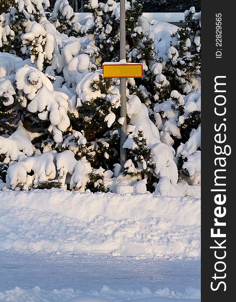 A blank yellow sign on a pole in a winter scene. A blank yellow sign on a pole in a winter scene.