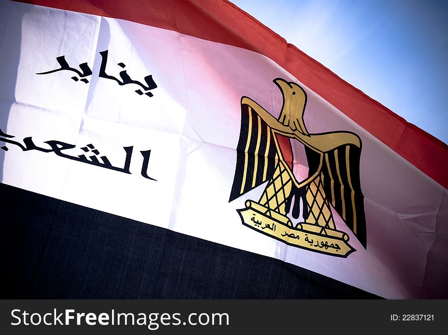 Egyptian flag in high dynamic range with blue sky in background , also the flag has the date of the egyptian revolution. Egyptian flag in high dynamic range with blue sky in background , also the flag has the date of the egyptian revolution