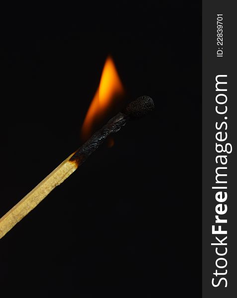 Burning match on black background