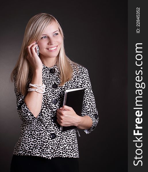 Business woman with phone and notebook on black background