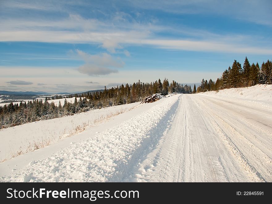 Snow mountain winter road on fir tree forest and blue sky background