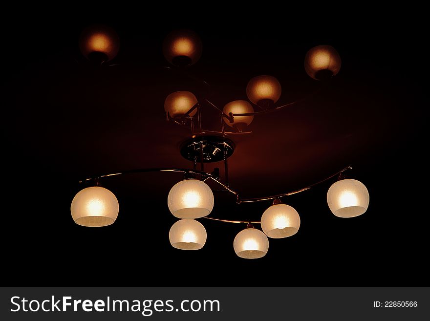 Glowing electric chandelier with round lampshades from glass