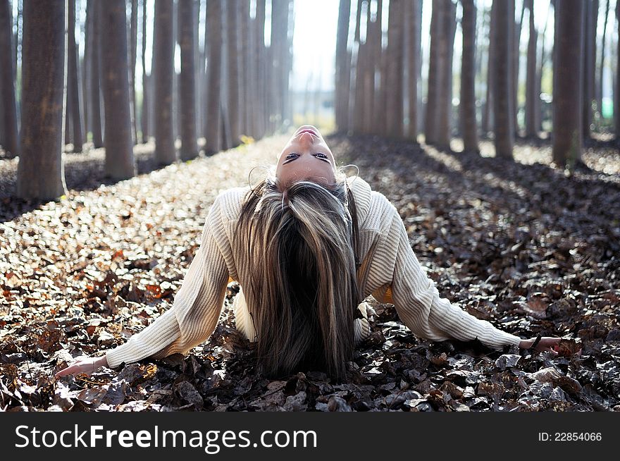 Beautiful blonde girl lying on leaves in a forest of poplars