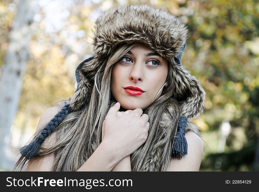 Portrait of beautiful girl with the winter hat on, in the park